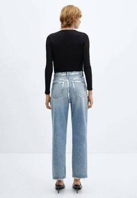 Zwarte lange mouwen top in combinatie met lichtblauwe high-waisted jeans. De jeans hebben een comfortabele pasvorm en rafelige zoom, met achterzakken.
