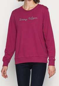 Sudadera fucsia de mezcla de algodón, con el logo bordado de "Tommy Hilfiger", puños y dobladillo acanalados, y acento del logo en la manga.