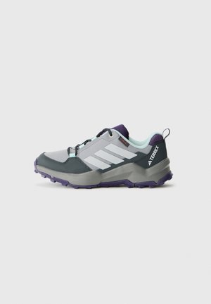 Chaussure de randonnée Adidas Terrex grise et violette avec des lacets noirs, semelle texturée et doublure intérieure bleu clair, vue de côté sur fond blanc.