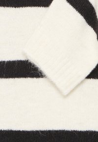 Knitted sweater with cream and black horizontal stripes, featuring a soft texture and a ribbed collar. Detailing includes a folded sleeve cuff.