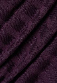 Textil mit Struktur in tiefem Lila, das ein Muster aus erhabenen Quadraten und Streifen aufweist. Das Material wirkt gestrickt und hat eine weiche, gewebte Textur.