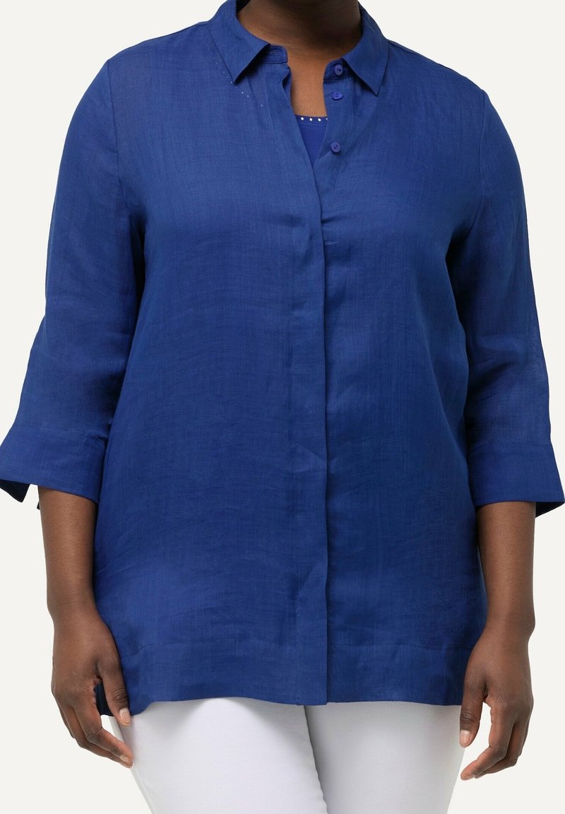 Marinblå linneskjorta med krage, trekvartslånga ärmar och knäppning fram. Slät textur; något avslappnad passform; utan mönster.