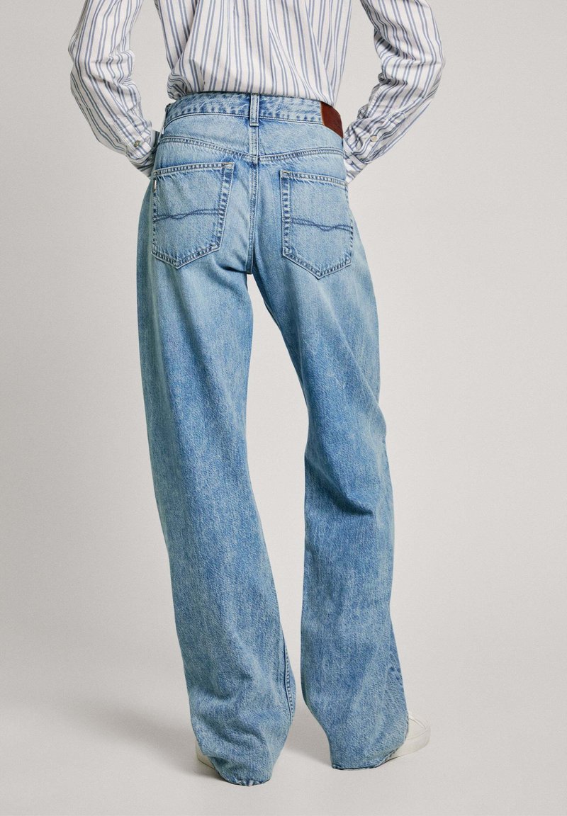 Jeans a gamba larga in denim azzurro chiaro. Presentano una vita alta, due tasche posteriori e un'etichetta in pelle marrone sulla vita. Texture morbida.