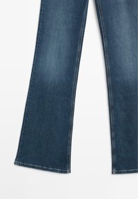 Jeans in denim blu scuro con un design a gamba svasata. Presentano cuciture standard e un orlo pulito senza ulteriori abbellimenti.