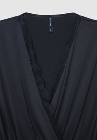 Schwarzes Wickelkleid aus glattem Stoff mit tiefem V-Ausschnitt, das entlang der Kanten eine zarte Spitzenborte aufweist und ein Etikett innen hat.