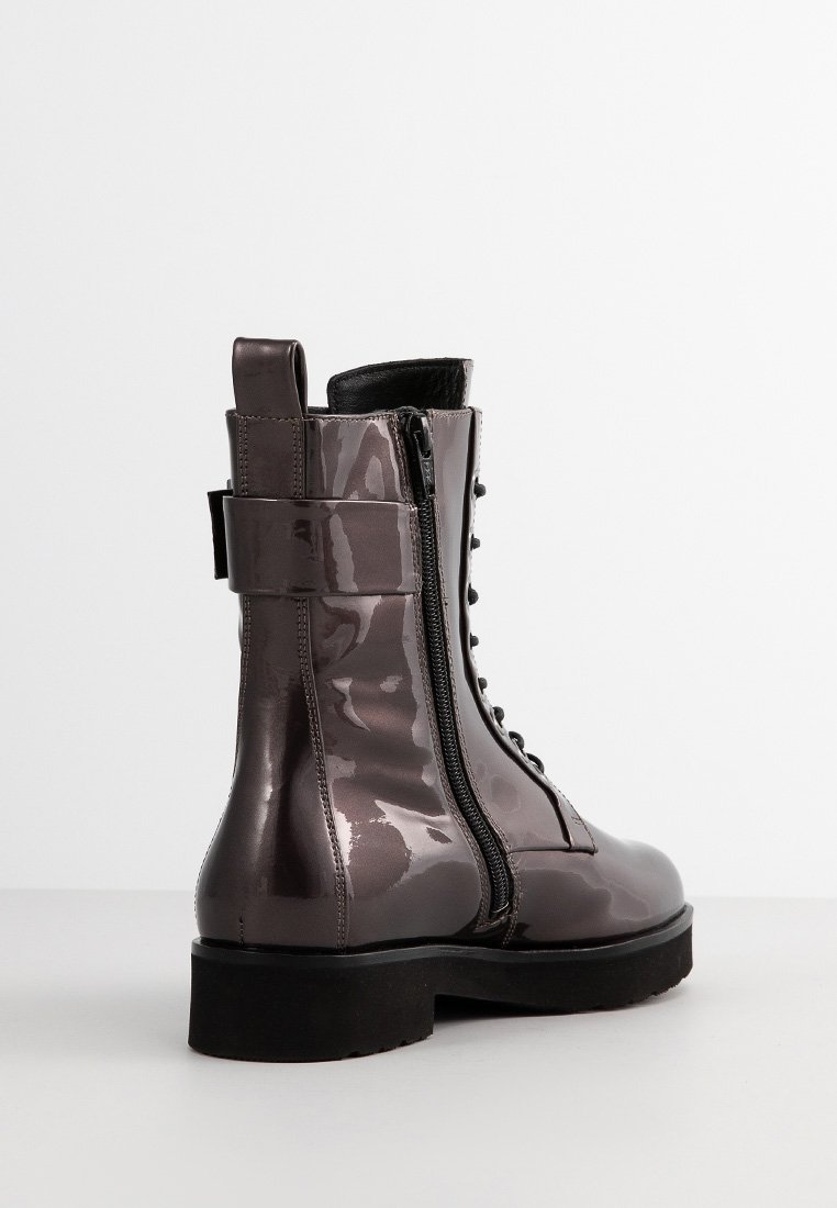 Glänzende dunkelgraue Schnürkampfstiefel mit seitlichem Reißverschluss, dicker schwarzer Sohle und breitem Knöchelriemen vor einem schlichten hellen Hintergrund.