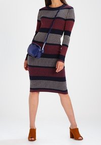 Vestido de punto con mangas largas, que presenta rayas horizontales en burdeos, azul marino y crema. Combinado con un pequeño bolso azul marino y mule marrones.