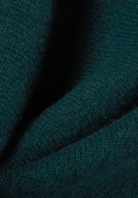 Türkiser Wollstoff mit einer weichen, strukturierten Oberfläche; weist ein enges Strickmuster und unterschiedliche Webdetails auf.