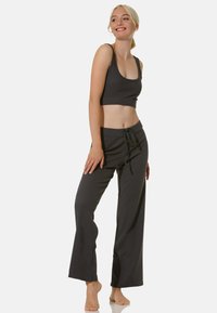 Cropped top grigio scuro con spalline larghe abbinato a pantaloni grigi scuri a vestibilità ampia con vita regolabile. Tessuto morbido e liscio.