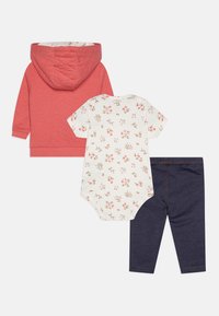Quilted coral hoodie with a hood, floral-patterned white bodysuit, and dark denim leggings with orange stitching. Three-piece outfit set.