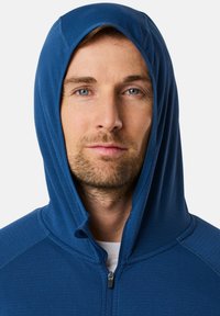 Felpa con zip blu, dotata di una chiusura frontale, cappuccio, texture morbida e dettagli cuciti lungo le cuciture.