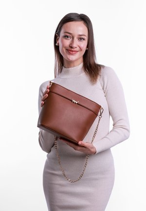 Braune Leder-Eimer-Handtasche mit einem goldfarbigen Kettenriemen und einem markanten goldenen Akzent an der Vorderseite. Glatte Textur und strukturierte Form.