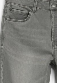 Pantalones de mezclilla grises con una textura suave, diseño de cinco bolsillos y acentos de metal. Presentan costuras de contraste a lo largo de las costuras.