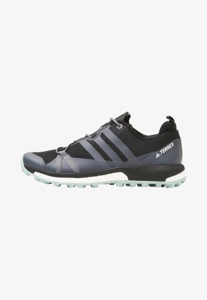 Chaussure de trail Adidas Terrex noire et grise avec semelle texturée et amorti blanc, vue latérale sur fond blanc.