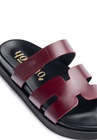 Burgundy leather slide sandal with cut-out design, black insole, and rubber sole. Gold brand logo on the footbed.