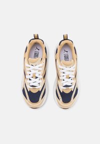 Sneaker con tomaia in mesh beige e navy, suola in gomma a contrasto, lacci bianchi e una linguetta sul tallone per facilitare l'indossamento.