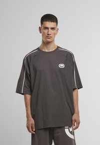 Grafisk grå t-shirt med korte ærmer, med hvide accentsting og et lille logo på brystet; lavet af blødt bomuldsstof.