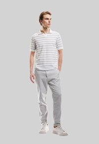 Polo shirt i hvid med grå striber, parret med lysegrå bukser og hvide sneakers. Moderne pasform med klassisk krave. Blød tekstur.