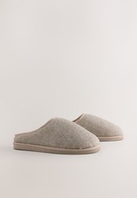 Sivé vlnené papuče s rybej kostrovým vzorom, jemnou textúrou, béžovým lemovaním a plochými, polstrovanými podrážkami. Lehká a otvorená zadná časť.