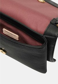 Borsa a tracolla in pelle nera con superficie текстurizzata, dotata di fodera interna color malva, hardware dorato e un'etichetta del marchio visibile all'interno.