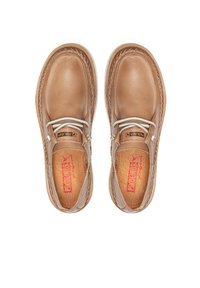 Zapatos de cuero marrón claro con acabado suave, costuras expuestas y un acento de cordón plateado; las plantillas presentan un logo rojo.