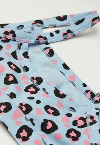 Modrá látka s černými a růžovými leopardími skvrnami, se zaobleným výstřihem a švy. Materiál se zdá být měkký s elastickými ramínky.