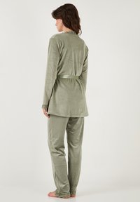 Olijfgroen loungewear-set met een lange mouwen top met een gegolfde halslijn, bijpassende broek met kantdetails, gemaakt van zachte stof.