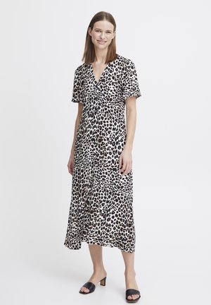 Robe à imprimé léopard avec des manches courtes, décolleté en V, tissu fluide, longueur genoux, ornée de boutons sur le devant, associée à des sandales à talons noires.