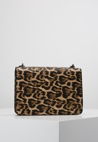Torebka w panterkę z brązowego i czarnego futerka sztucznego, prostokątnego kształtu z płaskim dnem oraz srebrnymi ozdobami.