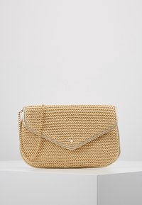 Ratanová taška v béžové barvě s víkem, kovovým lemováním a řetízkovým popruhem. Na přední straně je malý kovový hřebík jako detail.