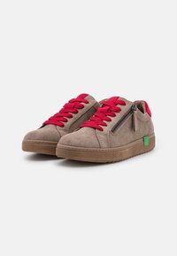 Scarpe in suede marrone con lacci rossi, zip laterale e accento del logo verde. Design a profilo basso con suola in gomma testurizzata e dettagli cuciti.