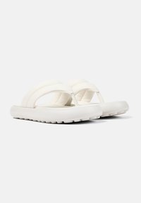 Vita flip-flops med två breda remmar, mjukt texturerat material, en tjock sula och mönstrad undersida för grepp.