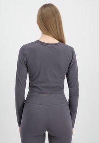 Grå langermet crop top laget av myk stoff, med rund hals og tettsittende design, sammen med matchende høy midje leggings.