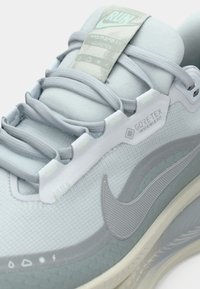 Jasnoniebieskie buty biegowe z siateczkowej cholewki, teksturowanymi akcentami, metką Gore-Tex oraz wyraźnym logo Swoosh z boku.