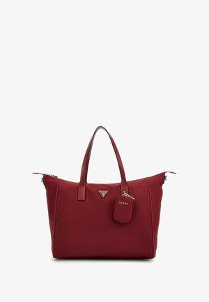 Sac fourre-tout rouge en matériau synthétique avec deux poignées, fermeture zippée, logo triangulaire et étiquette amovible. Texture lisse.