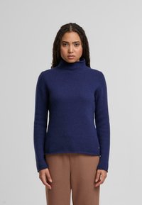 Dunkelblauer Rollkragenpullover aus geripptem Strickmaterial mit langen Ärmeln und geradem Saum. Dezente Schlitzdetails an der Unterseite.