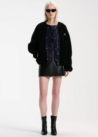 Black fleece bomber jacket with a quilted navy lining, silver snap buttons, paired with a black leather mini skirt and black ankle boots.