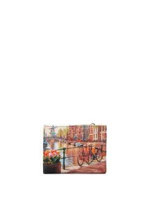 Canale con barche, edifici in mattoni, due biciclette legate alla ringhiera e un vaso di fiori con tulipani arancioni lungo il bordo dell'acqua.