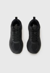 Black athletic shoes with a mesh upper, padded collar, and lace-up closure. Features a textured rubber sole and minimalistic design.