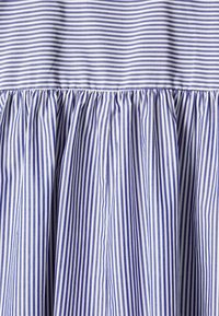 Tissu rayé bleu et blanc avec des rayures horizontales en haut et des rayures verticales réunies à la couture en dessous.