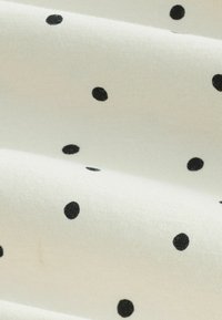 Puuvillane kangas valge taustaga, millel on mustade täpiliste erineva suurusega mustrite ühtlaselt jaotatud muster ning sile tekstuur.