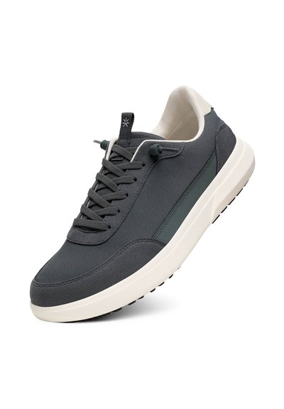 Tmavě šedé tenisky s texturovaným svrškem, šněrováním, kontrastní bílou podrážkou a jemnými zelenými detaily na bočním panelu.