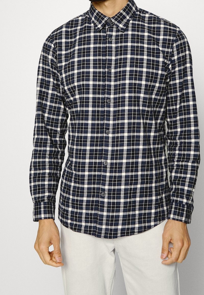 Button-up shirt in navy and white plaid pattern, made of cotton, featuring a classic collar and long sleeves.