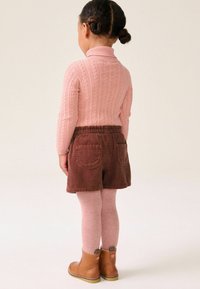 Rosa gestrickter Pullover, braune Cordshorts, rosa Strumpfhosen und braune Knöchelstiefel mit Nähdetails. Bequeme Passform, mittlere Bundhöhe, Gesäßtaschen.