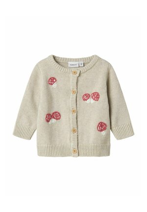 Cardigan en tricot beige clair avec col rond, boutons en bois et champignons rouges brodés sur les poches. Poignets et ourlet à côtes.
