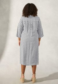 Abito stampato con maniche a ¾ in bianco e nero con motivo geometrico, lunghezza al ginocchio, tessuto leggero e delicato dettaglio con bottoni sul retro.