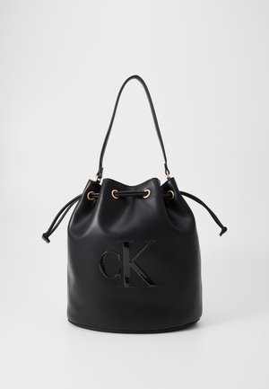 Bolso hobo de cuero negro con cierre de elástico, que presenta un brillante logo "CK" en el frente y detalles en tono dorado.