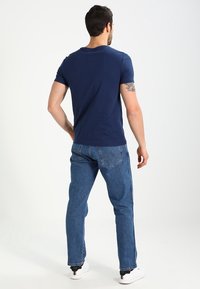 Men's navy blue cotton t-shirt paired with light blue denim jeans. The t-shirt features a classic crew neckline, and jeans have back pockets.