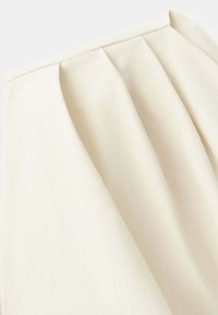 Jupe crème taille haute avec trois plis plats devant, ceinture lisse et tissu doux et structuré.