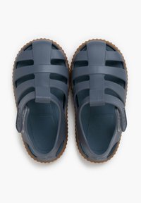 Gray rubber sandals featuring a closed toe and adjustable heel strap, with cut-out ventilation and a textured brown sole.